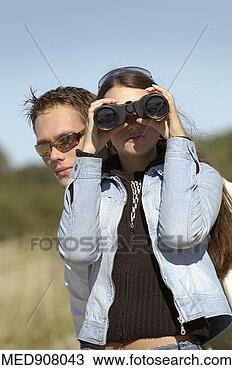 Stock Photo - couple watching 
something outdoors, 
 with woman using 
binoculars. fotosearch 
- search stock 
photos, pictures, 
images, and photo 
clipart