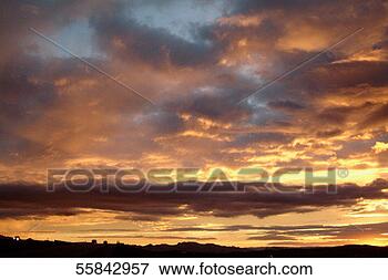 Picture - dramatic sunset 
under cloudy sky, 
 with vehicle 
with headlights 
on in. fotosearch 
- search stock 
photos, pictures, 
images, and photo 
clipart