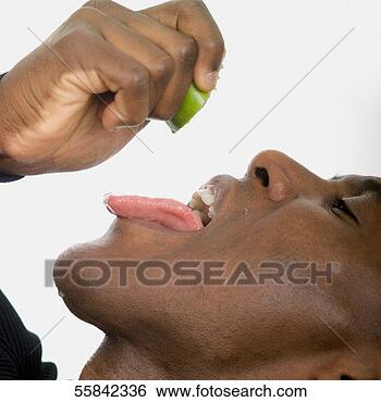 Stock Photo - man squeezing 
lime juice from 
lime into mouth, 
close-up. fotosearch 
- search stock 
photos, pictures, 
images, and photo 
clipart