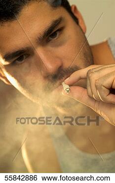 Stock Photo - young man smoking 
and surrounded 
by a cloud of 
smoke. fotosearch 
- search stock 
photos, pictures, 
images, and photo 
clipart