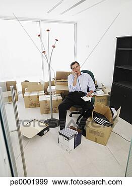 Stock Photograph - male office worker 
talking on phone 
while sitting 
in a new office. 
fotosearch - search 
stock photos, 
pictures, images, 
and photo clipart