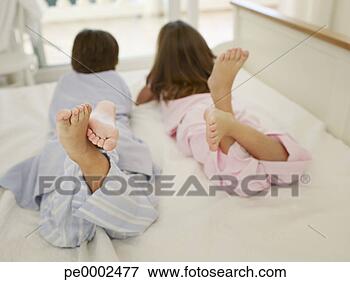 Picture - young brother 
and sister on 
a bed lying on 
their stomachs. 
fotosearch - search 
stock photos, 
pictures, images, 
and photo clipart