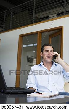 Stock Photography - businessman sitting 
in office on his 
mobile phone. 
fotosearch - search 
stock photos, 
pictures, images, 
and photo clipart