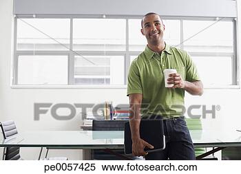 Stock Image - businessman standing 
in office with 
coffee cup smiling. 
fotosearch - search 
stock photos, 
pictures, images, 
and photo clipart