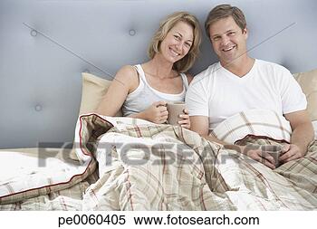 Stock Image - couple sitting 
in bed with mugs. 
fotosearch - search 
stock photos, 
pictures, images, 
and photo clipart