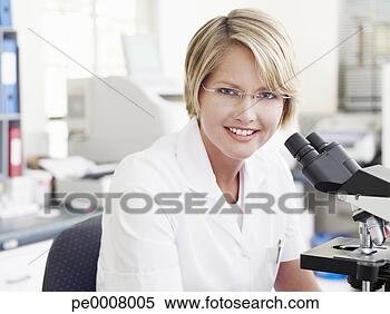 Stock Image - woman with eyeglasses 
sitting at microscope 
smiling. fotosearch 
- search stock 
photos, pictures, 
images, and photo 
clipart