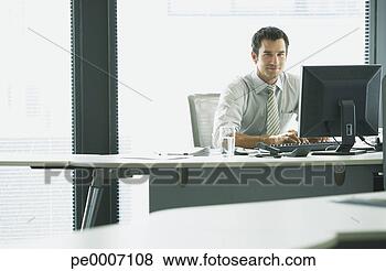 Stock Photo - businessman sitting 
at desk with computer 
working and smiling. 
fotosearch - search 
stock photos, 
pictures, images, 
and photo clipart