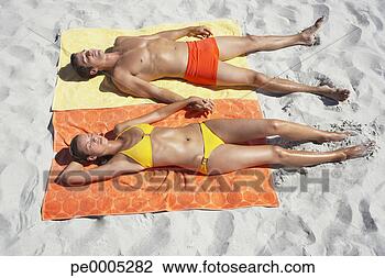 Stock Photo - man and woman 
sunbathing on 
beach towels in 
sand. fotosearch 
- search stock 
photos, pictures, 
images, and photo 
clipart
