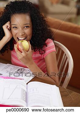 Arquivo de Fotografias - adolescente,  
menina,  sentando, 
 tabela,  dever 
casa,  comer, 
 maçã. fotosearch 
- busca de fotos, 
imagens e clipart