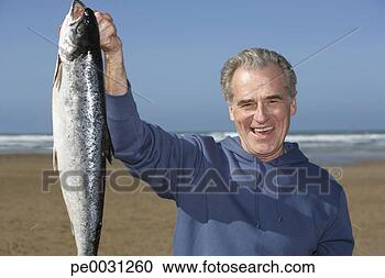 Stock Photography - man holding up 
a whole fish at 
the beach. fotosearch 
- search stock 
photos, pictures, 
images, and photo 
clipart