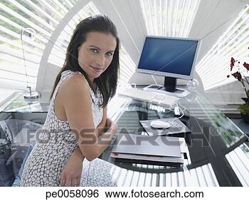 Stock Photo - businesswoman 
sitting at desk 
in modern office. 
fotosearch - search 
stock photos, 
pictures, images, 
and photo clipart