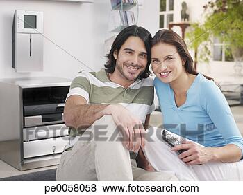 Stock Photo - couple sitting 
on rug holding 
television remote. 
fotosearch - search 
stock photos, 
pictures, images, 
and photo clipart