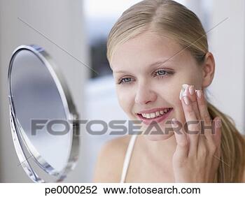 Banco de Imagem - mulher,  aplicando, 
 loção,  ou,  
creme,  rosto, 
 espelho. fotosearch 
- busca de fotos, 
imagens e clipart