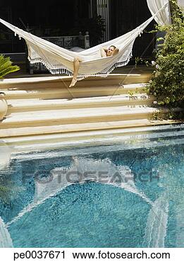 Stock Photography - woman relaxing 
in a hammock by 
a pool. fotosearch 
- search stock 
photos, pictures, 
images, and photo 
clipart