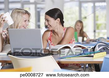 Foto - jovem,  mulheres, 
 laptop,  livros, 
 escola. fotosearch 
- busca de fotos, 
imagens e clipart