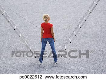 Stock Photo - woman standing 
outdoors on two 
ladders. fotosearch 
- search stock 
photos, pictures, 
images, and photo 
clipart