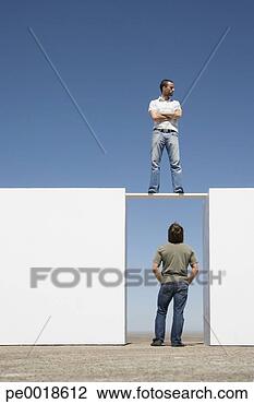 Stock Photo - man standing on 
board between 
two walls outdoors 
with man below. 
fotosearch - search 
stock photos, 
pictures, images, 
and photo clipart