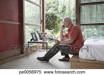 Stock Image - man on cellular 
phone sitting 
on bed with newspaper. 
fotosearch - search 
stock photos, 
pictures, images, 
and photo clipart