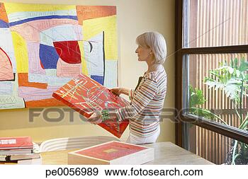 Stock Photograph - woman holding 
a painting in 
a modern home. 
fotosearch - search 
stock photos, 
pictures, images, 
and photo clipart