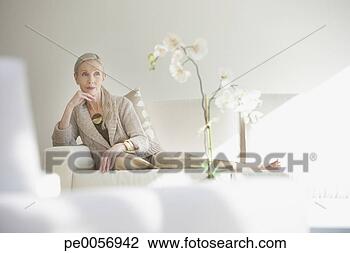 Stock Photo - woman sitting 
on a couch in 
a white room. 
fotosearch - search 
stock photos, 
pictures, images, 
and photo clipart