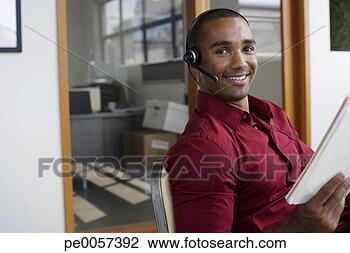 Stock Photo - businessman sitting 
in office wearing 
headset. fotosearch 
- search stock 
photos, pictures, 
images, and photo 
clipart