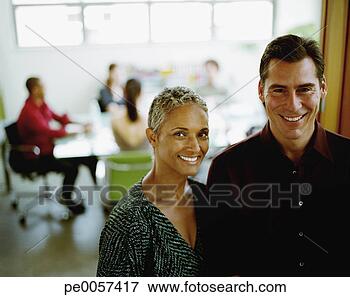 Picture - two businesspeople 
standing in office 
with coworkers 
in background. 
fotosearch - search 
stock photos, 
pictures, images, 
and photo clipart
