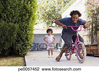 Stock Photo - father riding 
daughter's bicycle 
in driveway. fotosearch 
- search stock 
photos, pictures, 
images, and photo 
clipart
