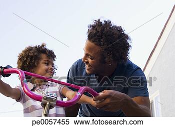 Stock Image - father teaching 
daughter to ride 
bicycle in driveway. 
fotosearch - search 
stock photos, 
pictures, images, 
and photo clipart