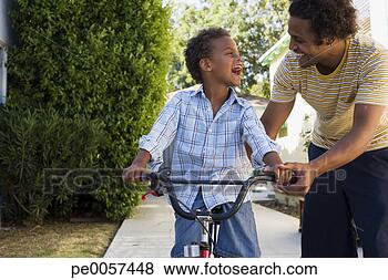 Stock Photo - father teaching 
son to ride bicycle 
in driveway. fotosearch 
- search stock 
photos, pictures, 
images, and photo 
clipart