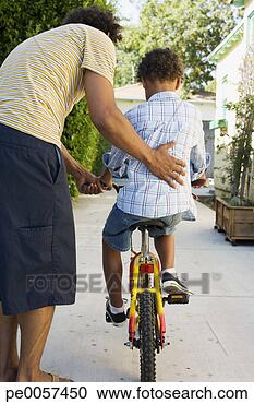 Stock Photography - father teaching 
son to ride bicycle 
in driveway. fotosearch 
- search stock 
photos, pictures, 
images, and photo 
clipart