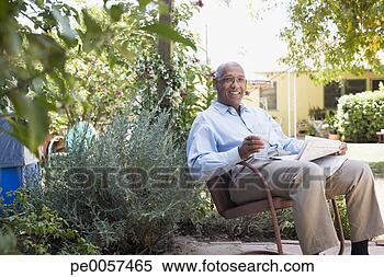 Stock Image - man on patio with 
newspaper and 
glass of water. 
fotosearch - search 
stock photos, 
pictures, images, 
and photo clipart