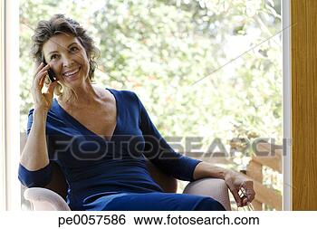 Stock Photo - woman on her mobile 
phone smiling 
indoors. fotosearch 
- search stock 
photos, pictures, 
images, and photo 
clipart