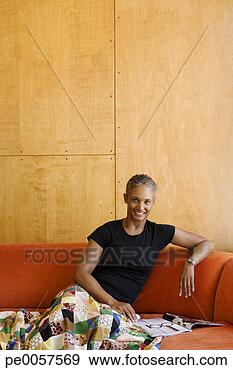 Stock Photograph - woman sitting 
on sofa with magazine 
in modern home. 
fotosearch - search 
stock photos, 
pictures, images, 
and photo clipart