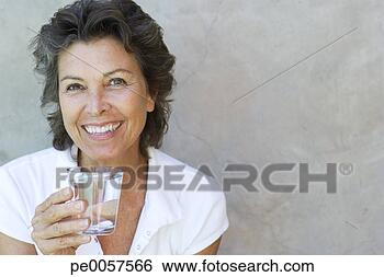 Stock Photo - woman smiling 
holding a glass 
of water outdoors. 
fotosearch - search 
stock photos, 
pictures, images, 
and photo clipart