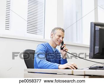 Picture - businessman on 
a telephone at 
his computer in 
an office. fotosearch 
- search stock 
photos, pictures, 
images, and photo 
clipart