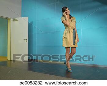 Stock Photo - businesswoman 
with mobile phone 
in blue office 
smiling. fotosearch 
- search stock 
photos, pictures, 
images, and photo 
clipart