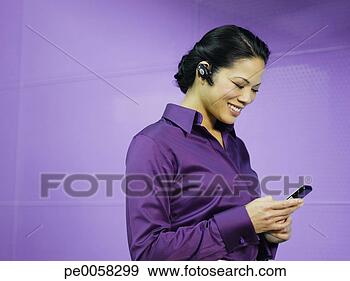 Stock Photograph - businesswoman 
with mobile phone 
and earpiece in 
purple office. 
fotosearch - search 
stock photos, 
pictures, images, 
and photo clipart