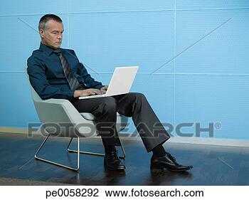 Banco de Imagem - homem negócios, 
 sentando,  laptop, 
 azul,  escritório. 
fotosearch - busca 
de fotos, imagens 
e clipart