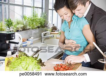 Stock Photography - couple embracing 
in a kitchen chopping 
cherry tomatoes. 
fotosearch - search 
stock photos, 
pictures, images, 
and photo clipart