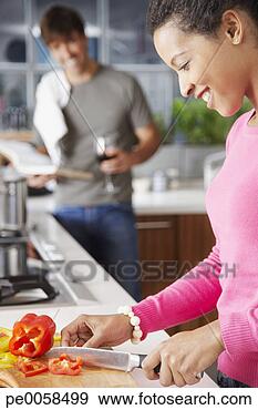 Stock Photograph - woman cutting 
red peppers with 
man in background. 
fotosearch - search 
stock photos, 
pictures, images, 
and photo clipart
