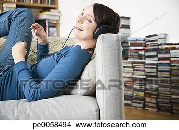Stock Photo - woman wearing 
headphones lying 
back on sofa. 
fotosearch - search 
stock photos, 
pictures, images, 
and photo clipart