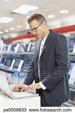 Stock Photo - man on laptop 
in a store. fotosearch 
- search stock 
photos, pictures, 
images, and photo 
clipart