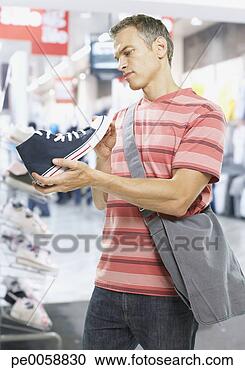 Stock Photography - man looking at 
shoes in store. 
fotosearch - search 
stock photos, 
pictures, images, 
and photo clipart