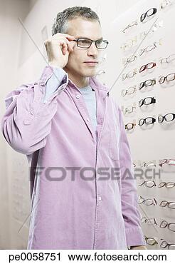 Stock Photography - man trying on 
glasses in optical 
shop. fotosearch 
- search stock 
photos, pictures, 
images, and photo 
clipart