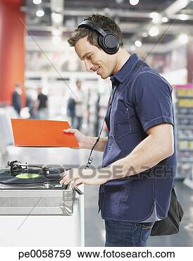 Stock Photograph - man wearing headphones 
at record player 
in store. fotosearch 
- search stock 
photos, pictures, 
images, and photo 
clipart
