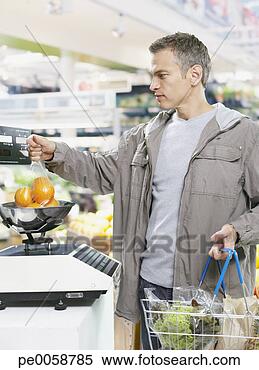 Stock Image - man weighing fruit 
while in grocery 
store. fotosearch 
- search stock 
photos, pictures, 
images, and photo 
clipart