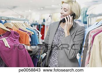 Stock Photo - woman shopping 
while on cellular 
phone. fotosearch 
- search stock 
photos, pictures, 
images, and photo 
clipart
