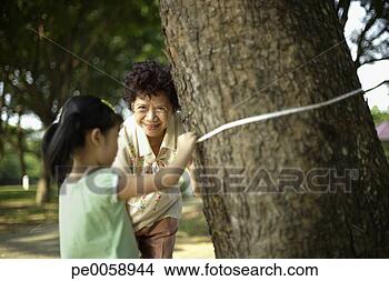 Stock Photo - woman and young 
girl tying measuring 
tape around tree 
trunk. fotosearch 
- search stock 
photos, pictures, 
images, and photo 
clipart