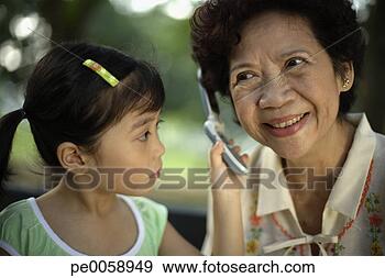 Stock Photograph - young girl holding 
phone to woman's 
ear. fotosearch 
- search stock 
photos, pictures, 
images, and photo 
clipart