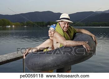 Stock Photo - couple standing 
in inner tube 
by lake. fotosearch 
- search stock 
photos, pictures, 
images, and photo 
clipart
